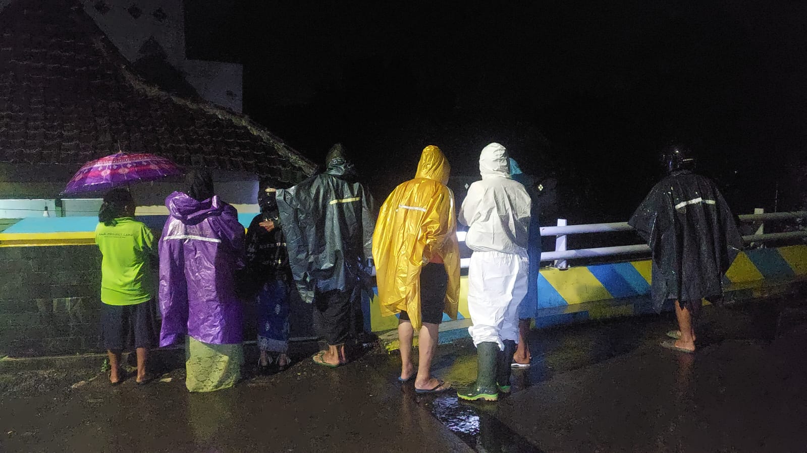MELIHAT DEBIT AIR: Warga sekitar dan perangkat desa Pakis melihat kondisi air sungai Petung yang terus membesar, Jumat (6/2). (JUMAI/RADAR JEMBER)