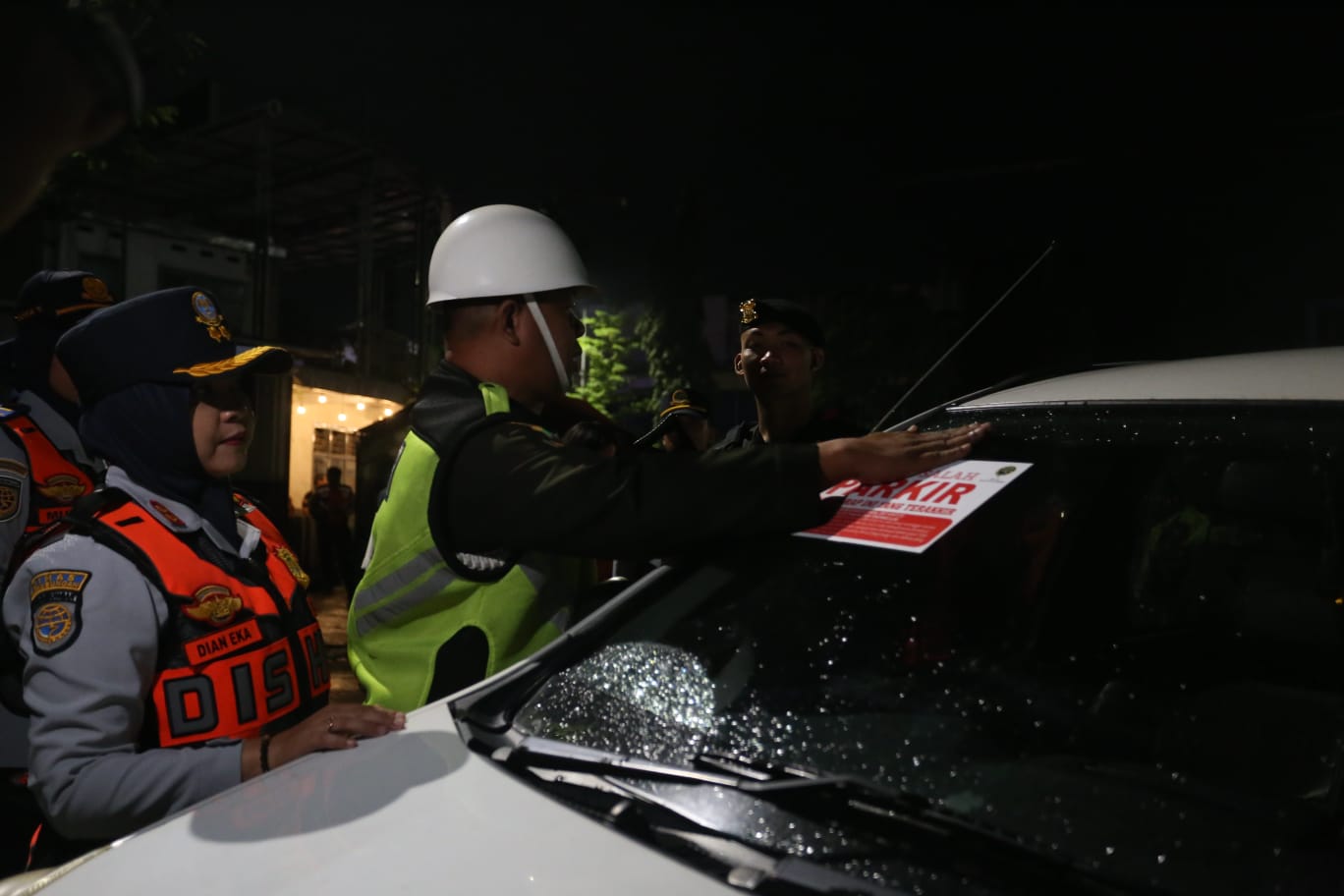 Petugas memasang stiker Anda Salah Parkir di ruas jalan di Jember, Sabtu (21/2/2026).
