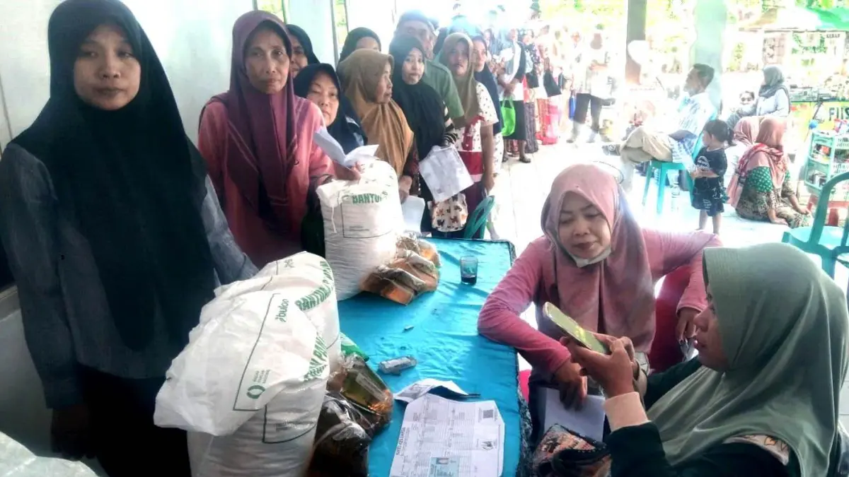 Warga Desa Sukorambi antre mengambil bantuan pangan di balai desa setempat, Jumat (22/5).