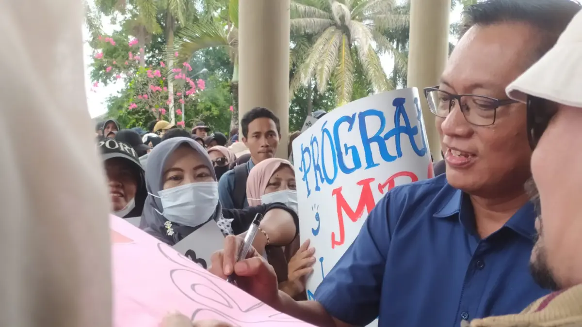Ketua DPRD Jember Ahmad Halim saat menandatangani poster yang digunakan massa aksi mendukung program MBG dan PSN lainnya di depan gedung dewan.