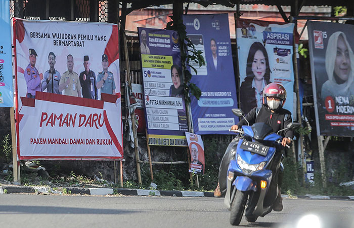 Pengendara motor melintasi deretan alat peraga kampanye (APK) di kawasan Sukanan, Pakem, Sleman, Selasa (19/12).