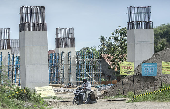 PROSES PEMBANGUNAN: Pengendara motor melintas berlatar pembangunan prouyek tol di kawasan Margodadi, Sayegan, Sleman kemarin (20/12).