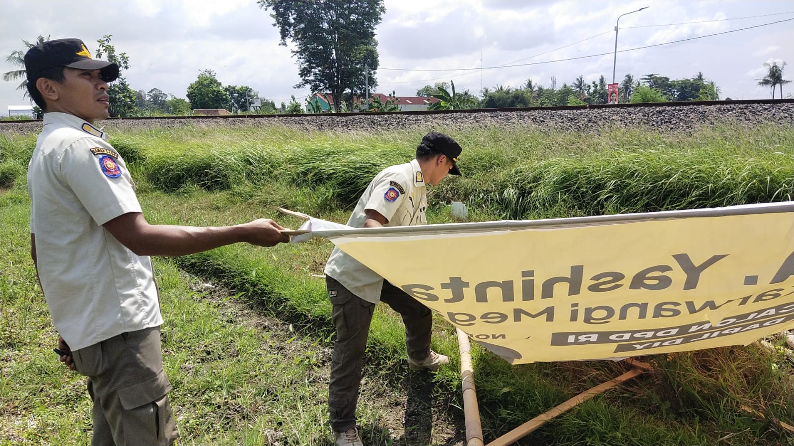 Petugas saat melakukan penertiban bendera partai politik dan APK yang berada di perlintasan kereta api pada Rabu (27/12).