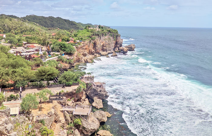 MANJAKAN MATA: Hamparan laut pantai selatan bisa dinikmati dari atas di Pantai Ngobaran Gunungkidul. Keberadaan beberapa tempat ibadah yang dibangun di sana juga menambah keunikan pantai.