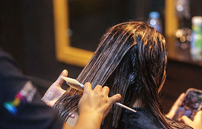 PROSES: Penata rambut di Medua Hair Salon saat mengoleskan krim keratin kepada konsumen kemarin (26/1). Rambut kemudian akan dikeringkan dan dicuci kembali untuk selanjutnya dicatok.