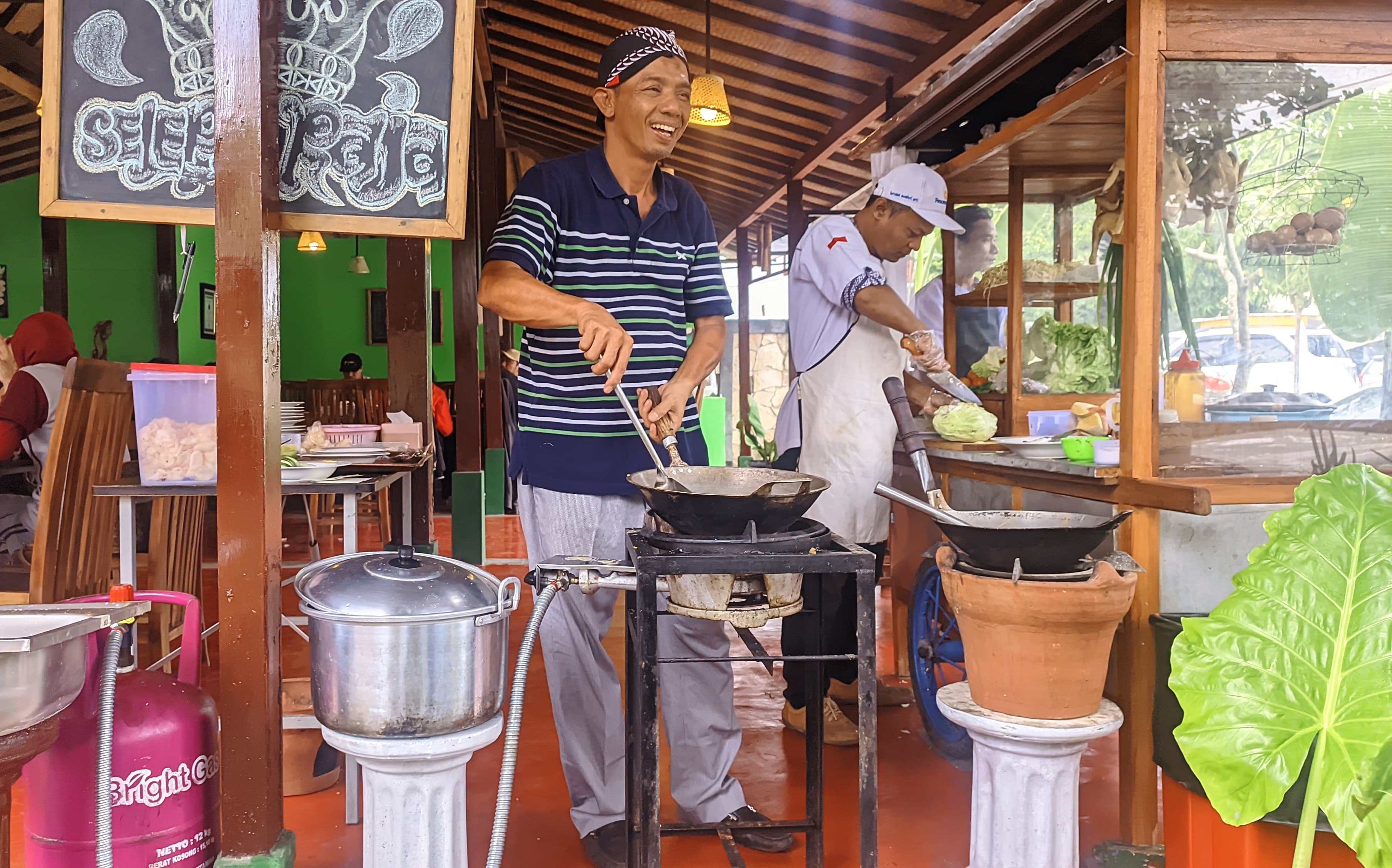 Eko yang pakai blangkon saat sedang memasak untuk menyiapkan pesanan konsumen.