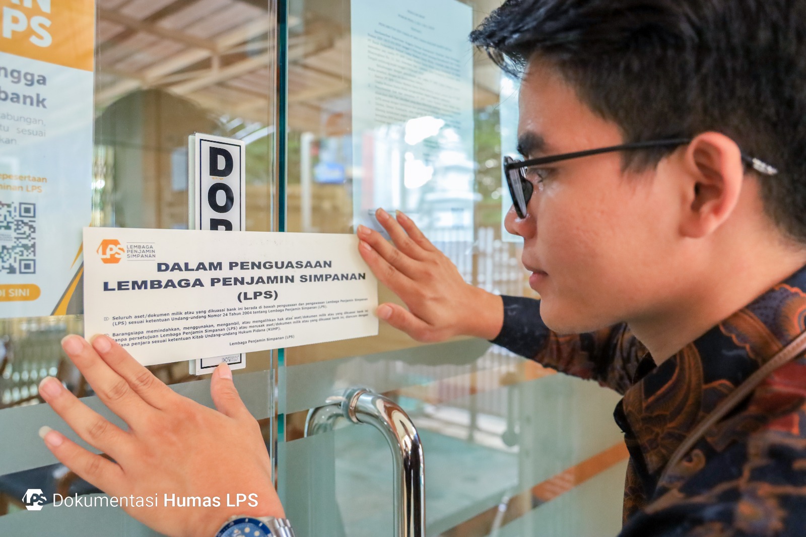 Petugas LPS menempel stiker informasi di BPR Usaha Madani Karya Mulia