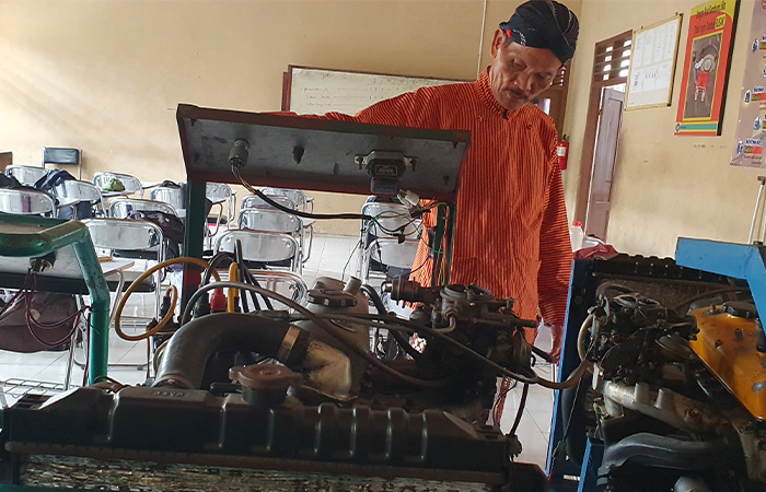 PRAKTIK LANGSUNG:  Guru kesiswaan SMKN 2 Wonosari Mujiyono berpose dengan peserta didik di ruang otomotif kemarin (7/2).