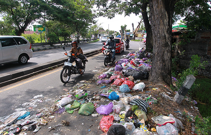 Pengguna jalan melintas di dekat tumpukan sampah yang berserakan di jalur lambat Ring Road selatan.
