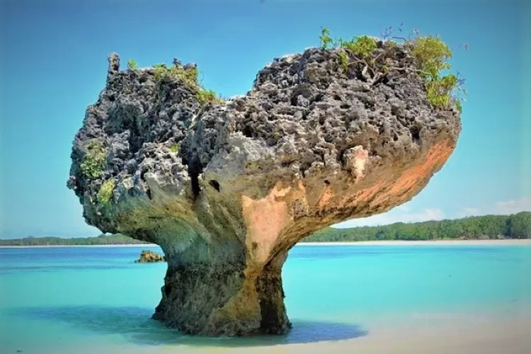 Pantai berpasir putih berbentuk hati dan laut biru di mulut Samudra