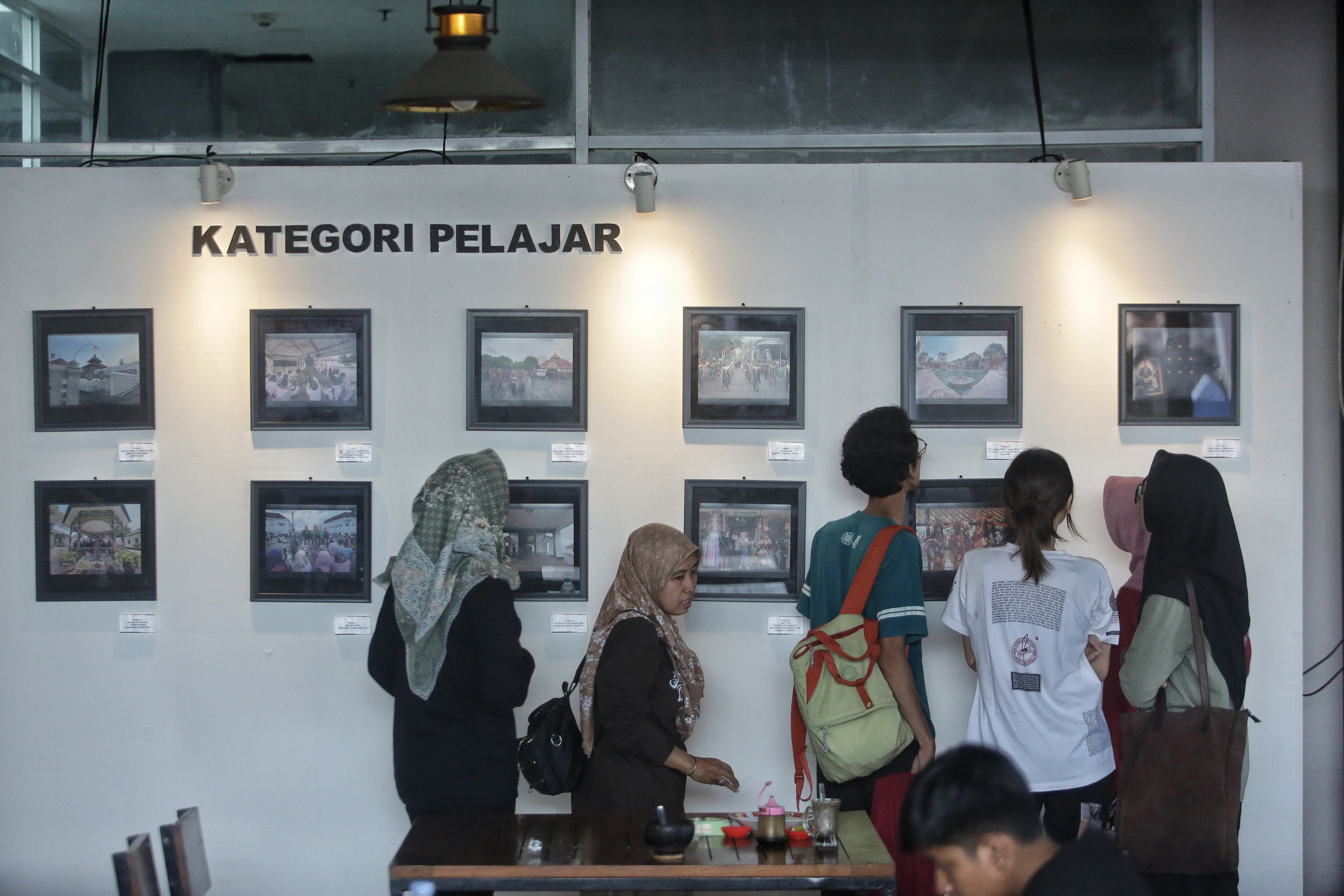 Pengunjung mengamati karya foto yang dipajnag saat pameran foto jogja dan festival film kampung di Rooftop Pasar Prawirotaman, Jogja, Jumat (21/6).