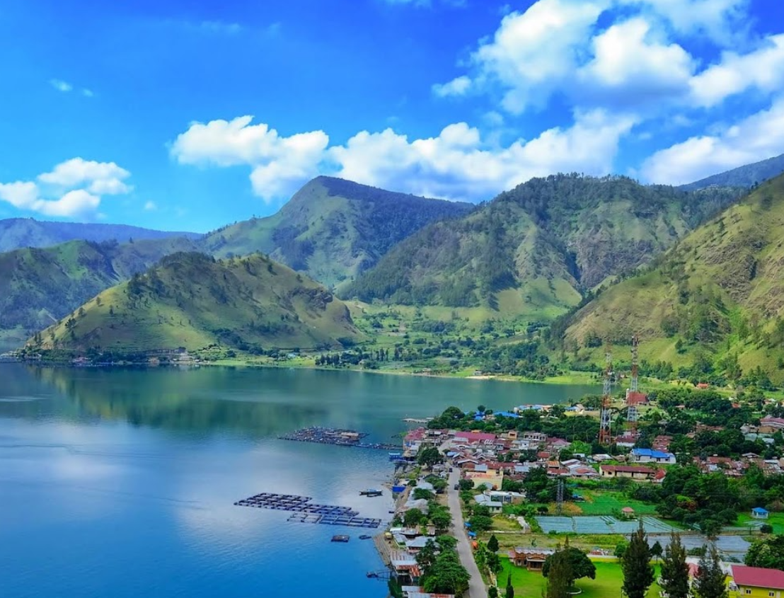 Air biru Danau Toba yang memukau, dikelilingi perbukitan hijau yang menawan.