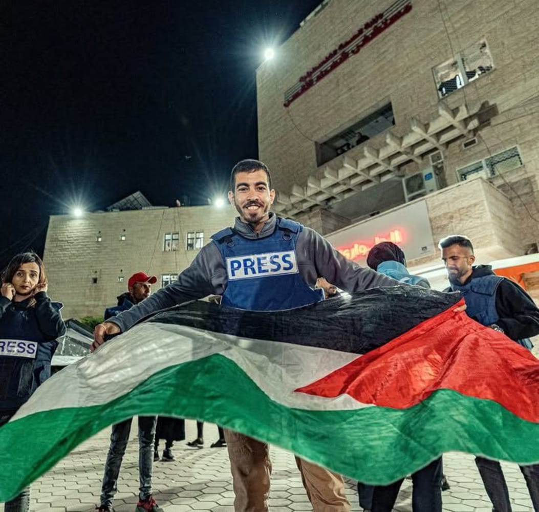Potret mendiang Saleh Aljafarawi saat mengenakan rompi pers dan mengibarkan bendera Palestina. (X/@S_Aljafarawi)