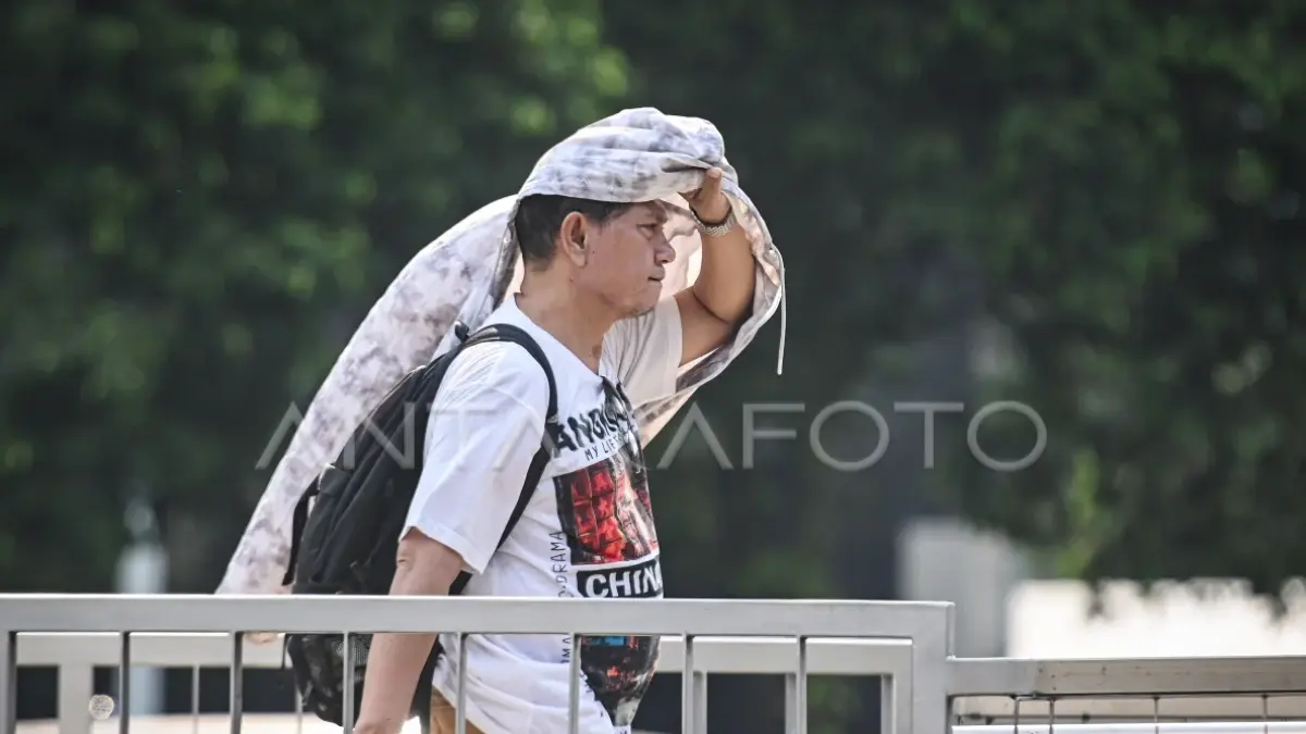 Seorang pria menutupi kepala dengan kain karena saking panasnya suhu. (Antara Foto)