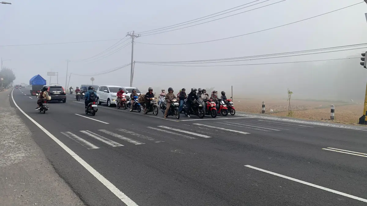 Pengendara sepeda motor berhenti di Simpang Tiga Tugu Pensil dengan suasana penuh kabut. (ANOM BAGASKORO/Radar Jogja) 