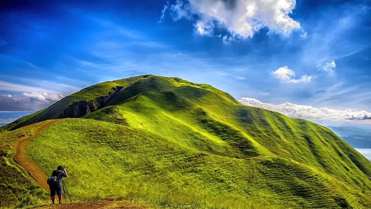 Pesona Bukit Holbung di Samosir menawarkan keindahan Danau Toba dari ketinggian dengan lanskap hijau bergelombang ala "Bukit Teletubbies" yang mudah diakses dan ideal untuk berkemah.