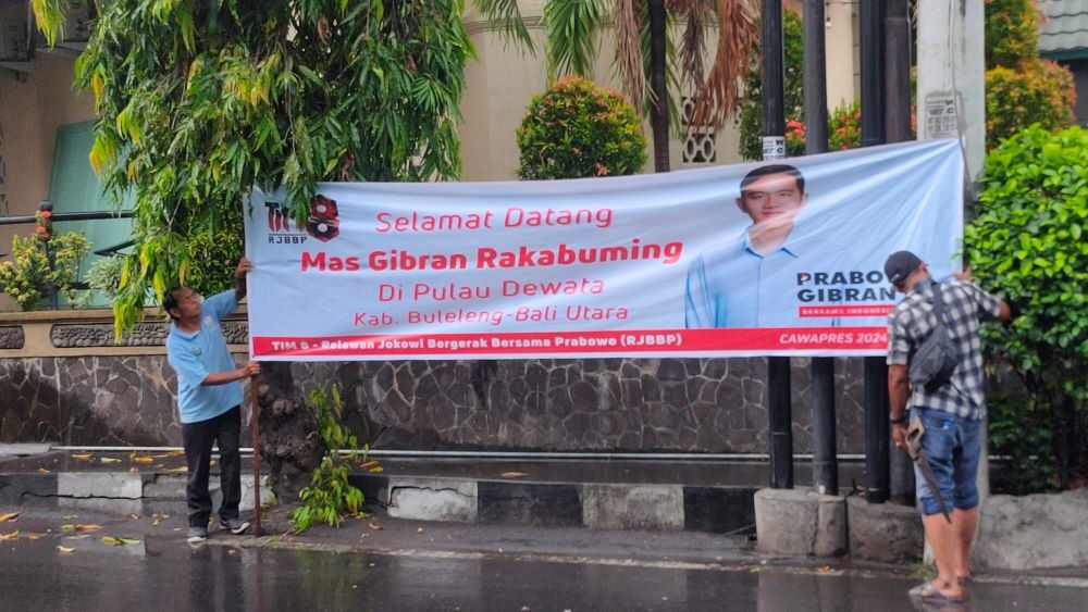 OPTIMIS MENANG: Relawan Gibran memasang spanduk selamat datang pada Cawapres Gibran di Buleleng.