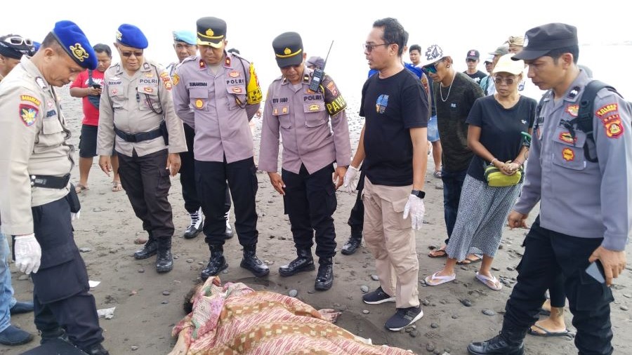 TANPA IDENTITAS: Polisi memeriksa jenazah Mrs.X yang tergeletak di pesisir Pantai Yeh Gangga, Tabanan, Jumat (12/1).