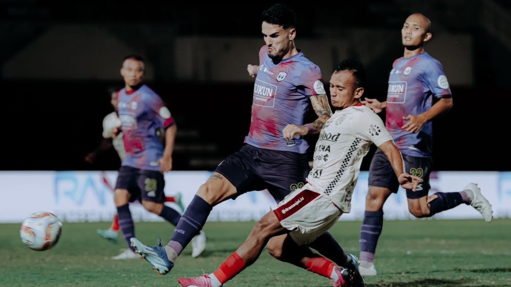 Winger Bali United, Irfan Jaya (putih) melesakkan bola dari kejaran pemain RANS Nusantara.