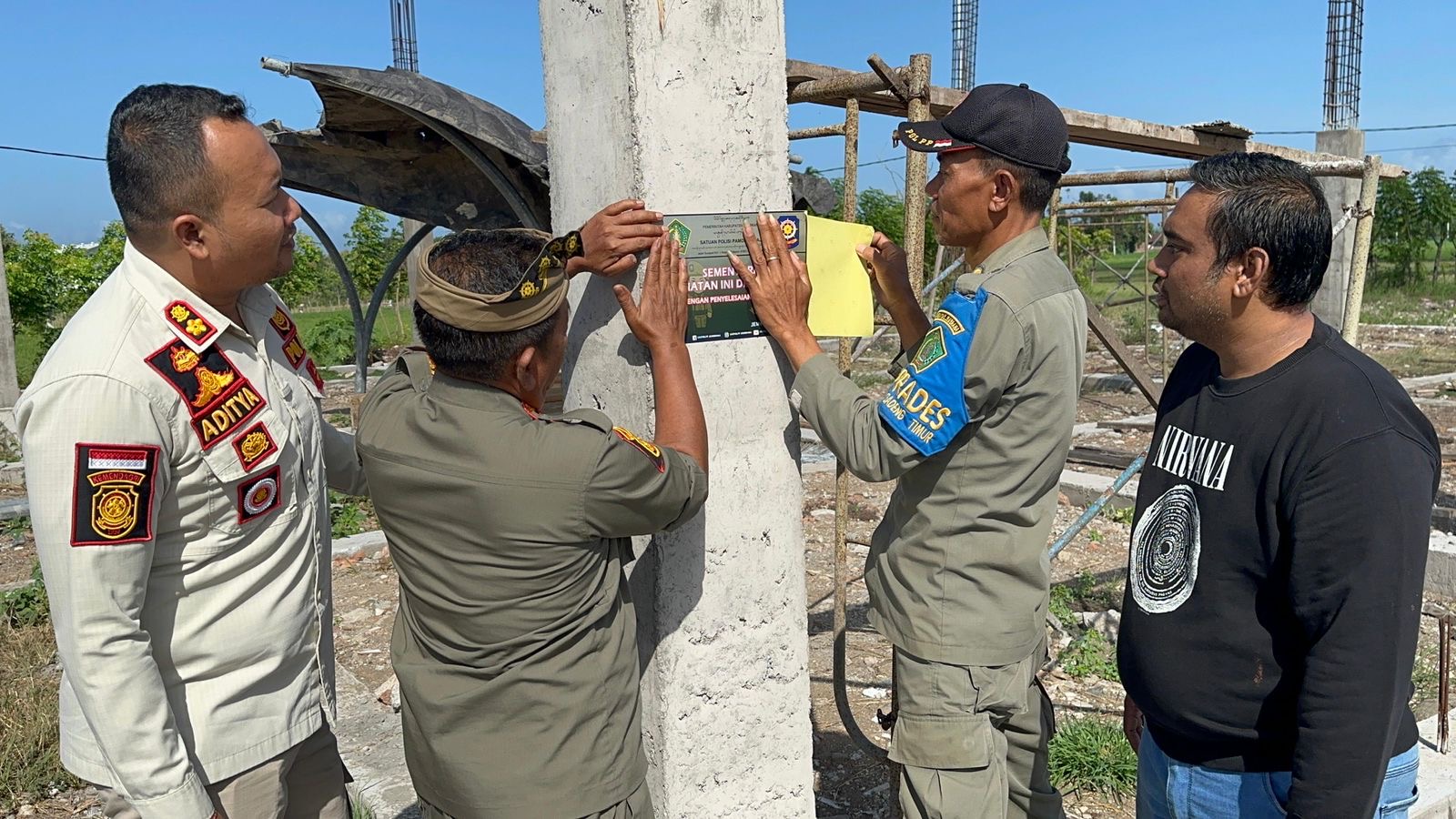 FOTO : Petugas Sapolpp Jembrana melakukan penempelan stiker pemberhentian sementara kegiatan pembangunan gedung kepentingan umum yang terletak di Desa Tegal Badeng Timur, Kecamatan Negara, Jembrana, K