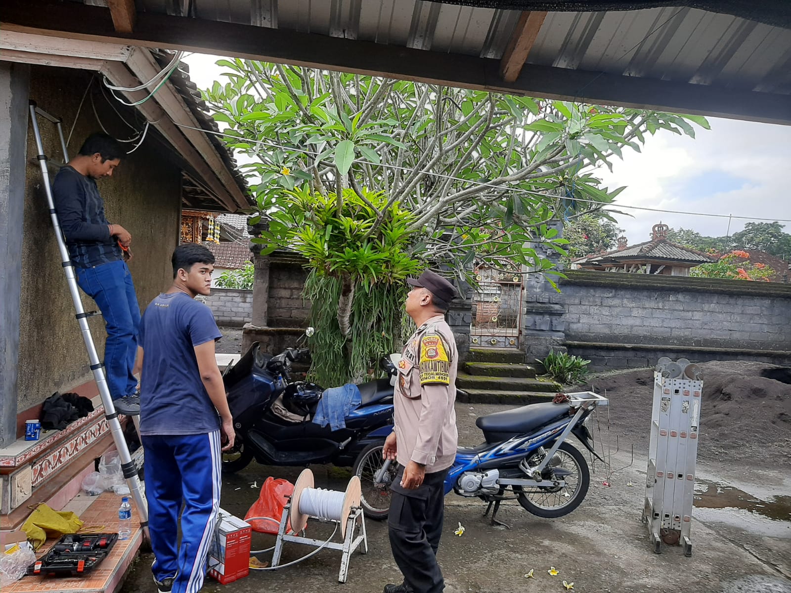 Anggota Polsek Selemadeg Timur mengawasi proses pemasangan kamera CCTV di Desa Tegalmengkeb, Tabanan, Senin (10/6)