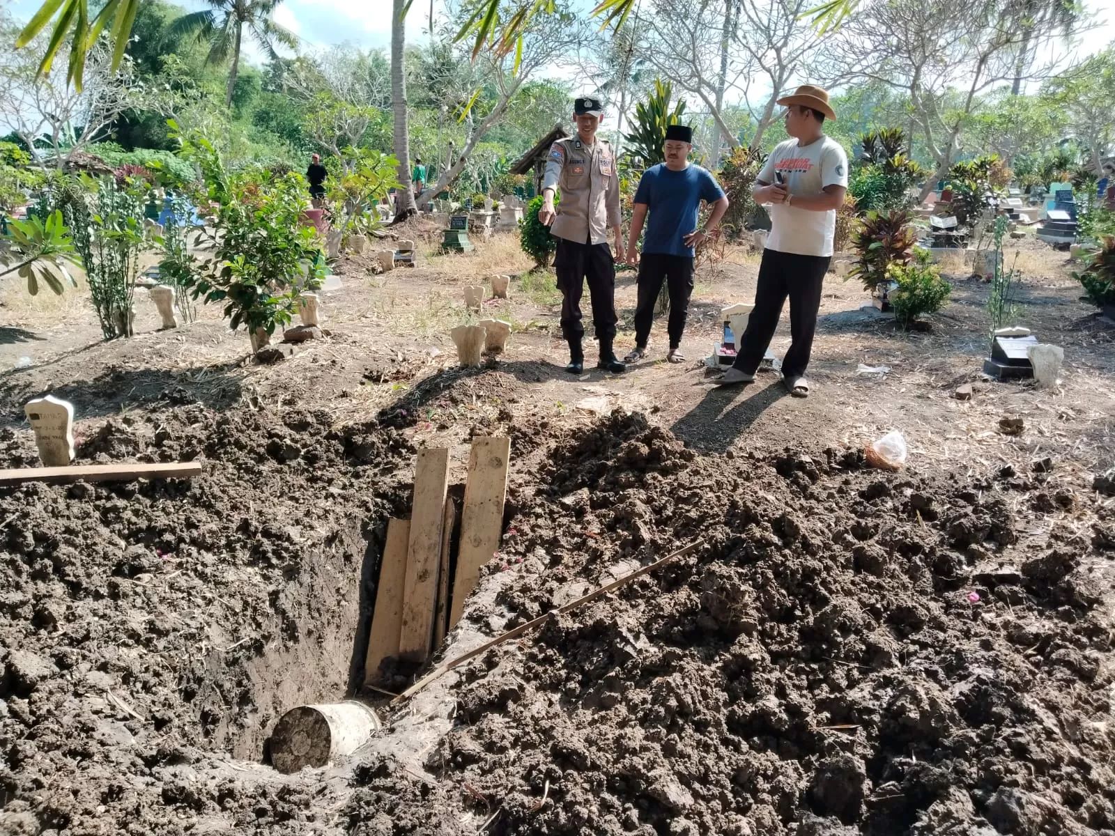 Polisi dan warga memeriksa makam warga Cluring Banyuwangi yang dibongkar orang tak dikenal dan tali pocongnya hilang.