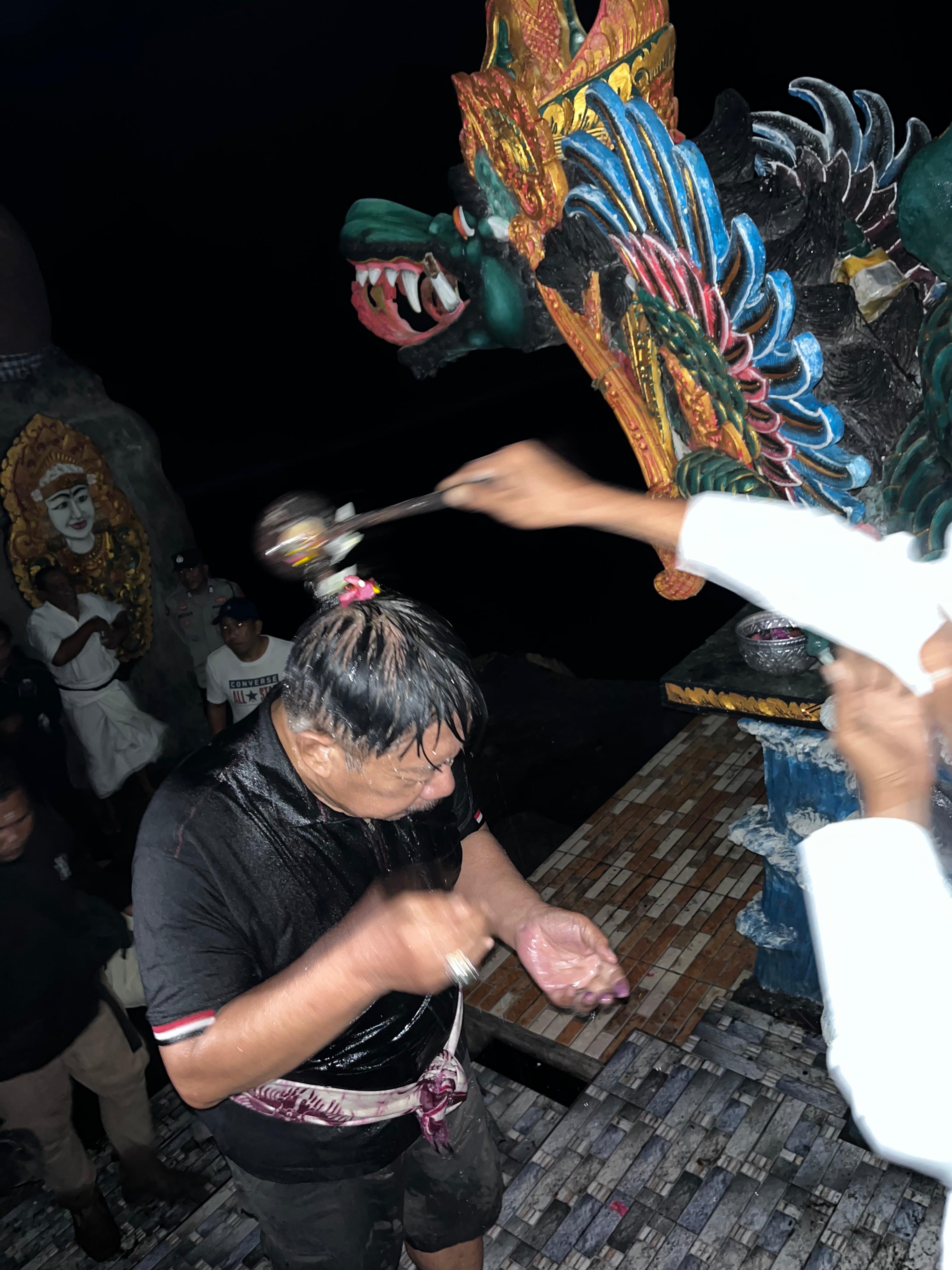 Proses pembersihan diri (melukat) I Gede Winasa yang dilakukan  Pemangku Pura Segara Yeh Kuning, Mendoyo, Jumat (5/7/2024).