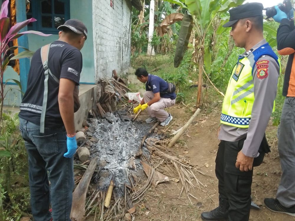 Polisi bagian identifikasi memeriksa sisa bara api tempat UH tewas terbakar di Jembrana.