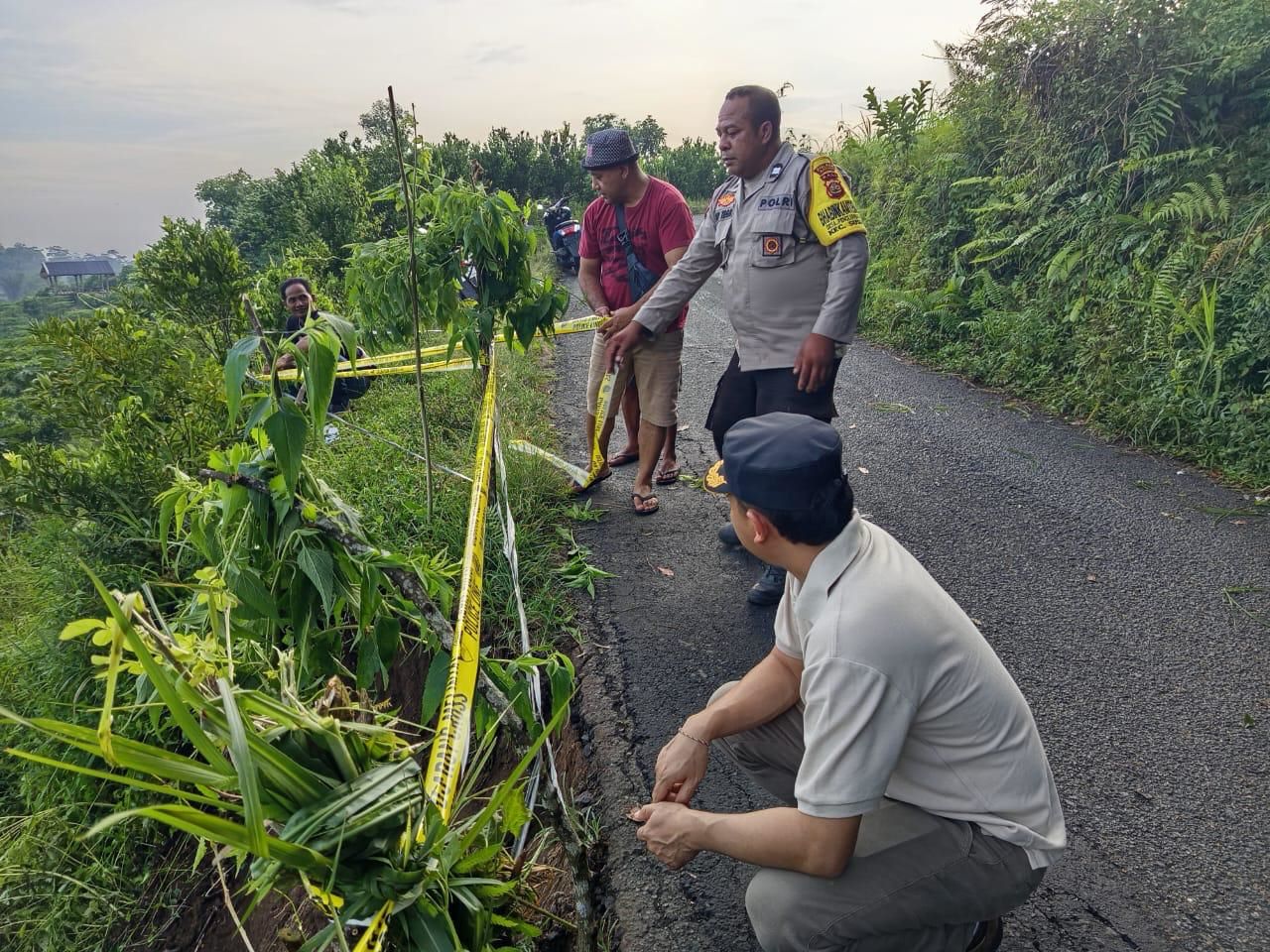 Polisi memasang garis polisi sebagai tanda adanya bahu jalan ambles di Susut Bangli.