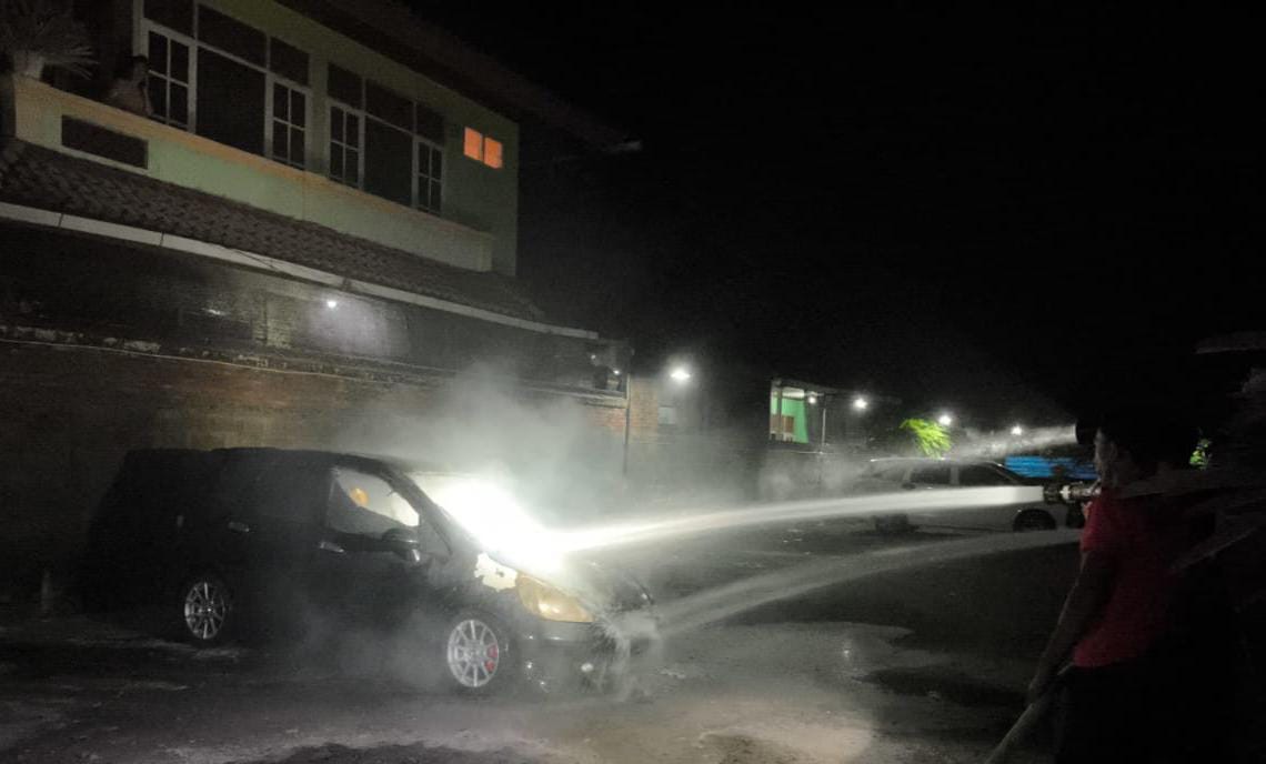 TEBAKAR : Damkar Jembrana berupaya memadamkan api yang membakar Honda Jazz diarea parkiran RS Bunda, Kelurahan Pendem, Jembrana.