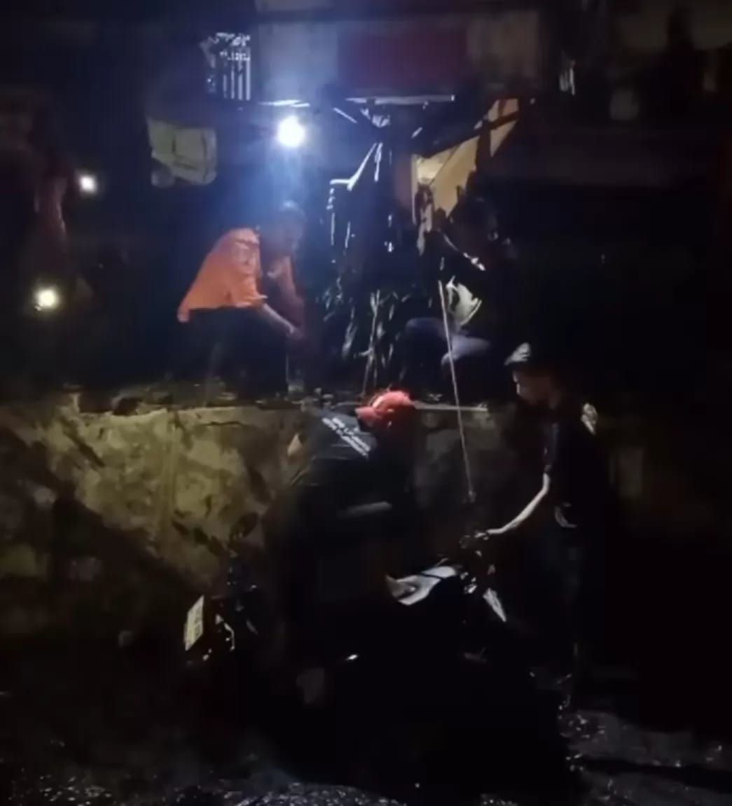 Petugas dibantu warga mengangkat motor korban kecelakaan di Jalan Mayar Surabaya.
