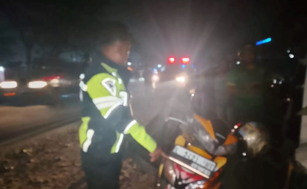 Polantas memeriksa kondisi pengendara motor yang meninggal mendadak di Jalan Byppass Krian Sidoarjo.