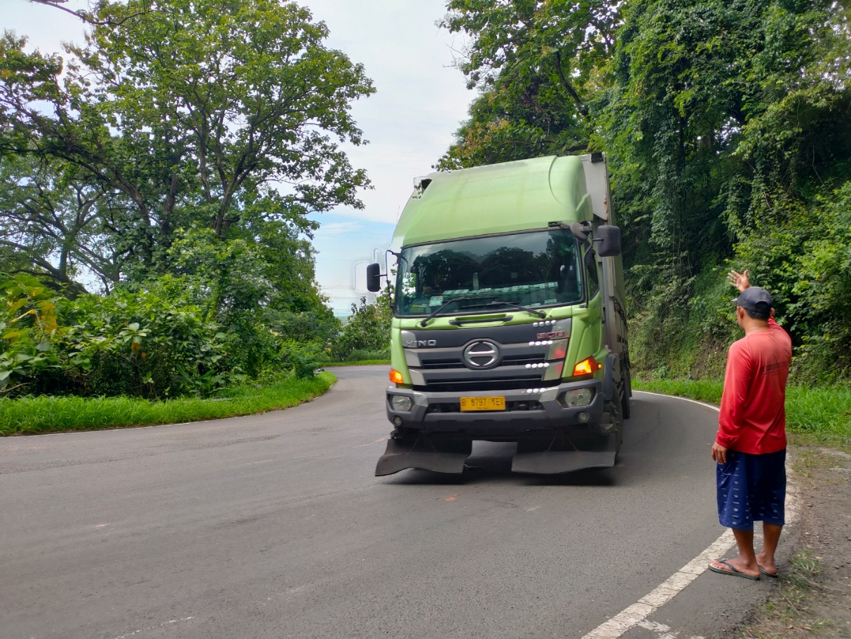 ATUR LALULINTAS: Warga sekitar sedang mengatur lalulintas di Jalan Daendels Kecamatan Gringsing. (Riyan Fadli Jawa Pos Metro Pekalongan)
