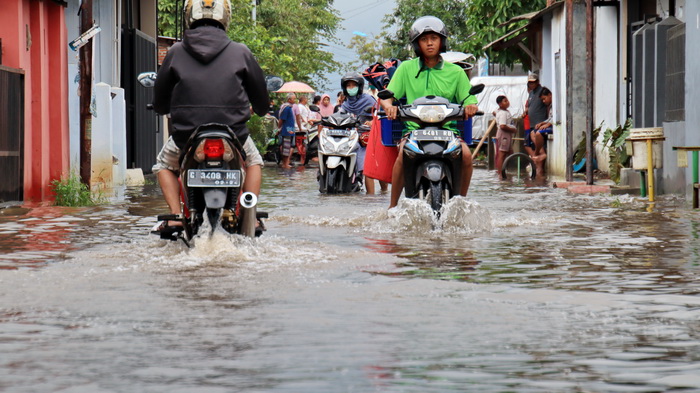 MELINTAS : Pengendara motor saat melintasi genangan banjir di suatu jalan di Kota Pekalongan.