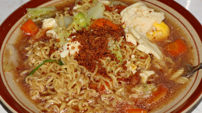 MIE: Mie instan rebus khas Indonesia yang lezat, disajikan dengan telur dan sayuran di piring.