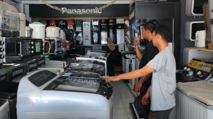 LAYANI KONSUMEN : Penjaga toko elektronik Berkah Jaya melayani pembeli mesin cuci pada Selasa (6/2/2024).