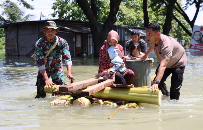 EVAKUASI KORBAN BANJIR : Petugas gabungan mengevakuasi warga korban banjir dengan getek pohon pisang dan kendaraan taktis di jalan Pantura Karanganyar yang masih terendam air.