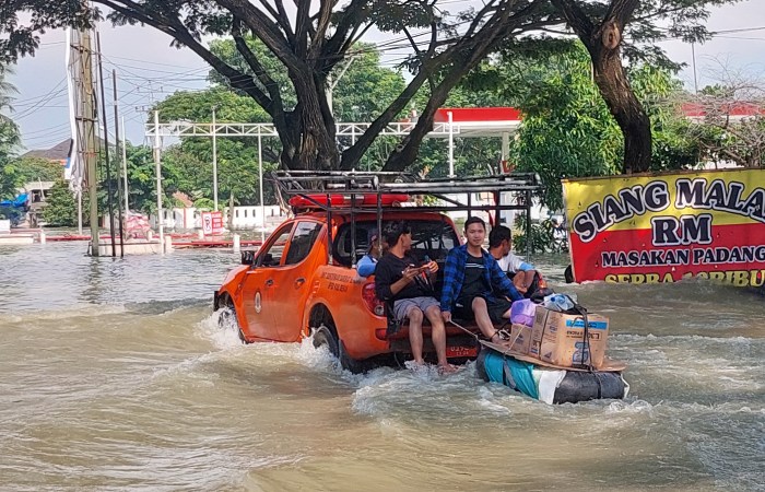 SISIR KORBAN BANJIR : Petugas gabungan mengevakuasi warga korban banjir di Jalan Pantura Karanganyar yang masih terendam air.