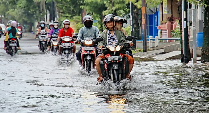 MELINTASI GENANGAN: Warga Kota Pekalongan terpaksa melintasi genangan di jalan Kurinci, karena masih salah satu akses utama.