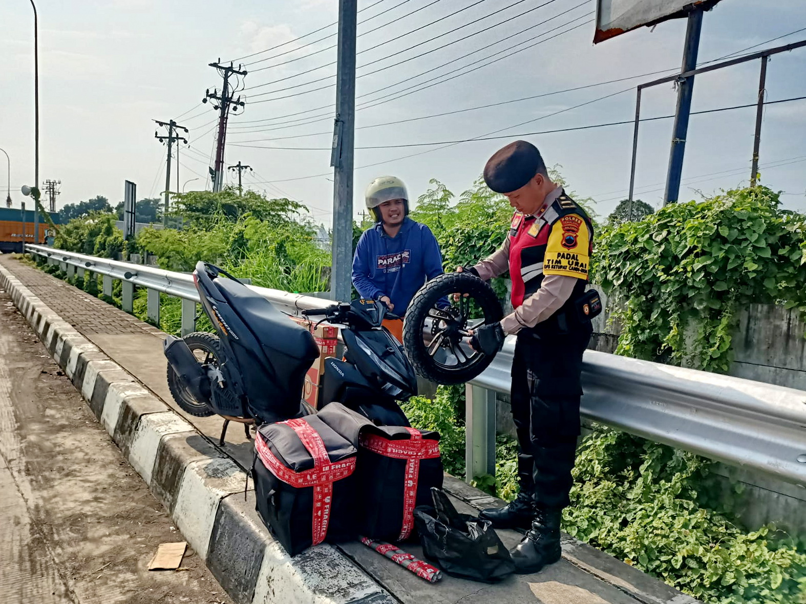 BANTU EVAKUASI: Melihat pemudik motor ban nya lepas, Anggota Polres Pemalang yang bertugas langsung bantu evakuasi, Jumat (5/4/2024).