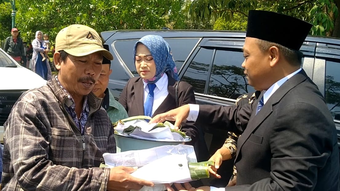 INSPIRATIF: Ahmad Ridhowi dan Umi Farida saat membagikan ikan pindang ke warga sebelum pelantikan mereka sebagai anggota DPRD Kabupaten Pekalongan, Rabu (14/8/2024).