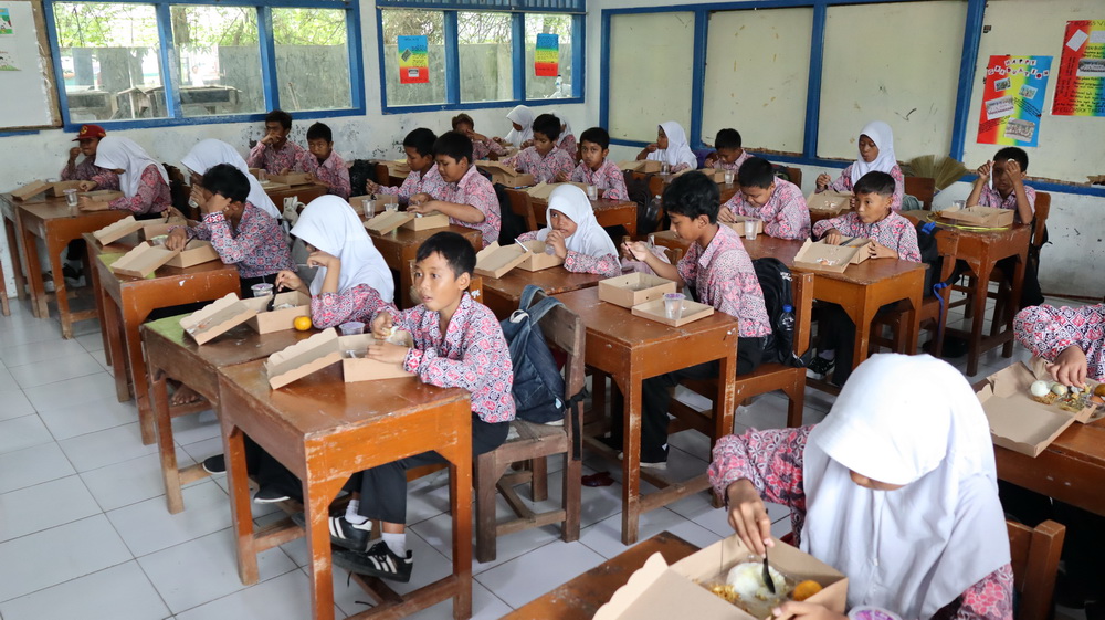 MENIKMATI MAKAN &ndash; Siswa SDN Panjang Wetan 03 saat menikmati makan siang gratis di sekolahnya.