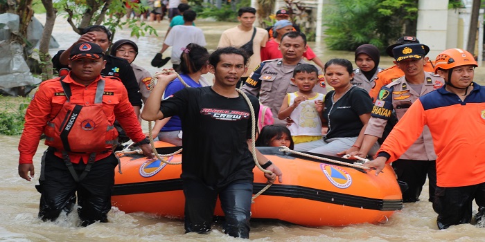 EVAKUASI WARGA : Petugas kepolisian dan tim SAR bahu membahu melakukan evakuasi warga terdampak banjir.