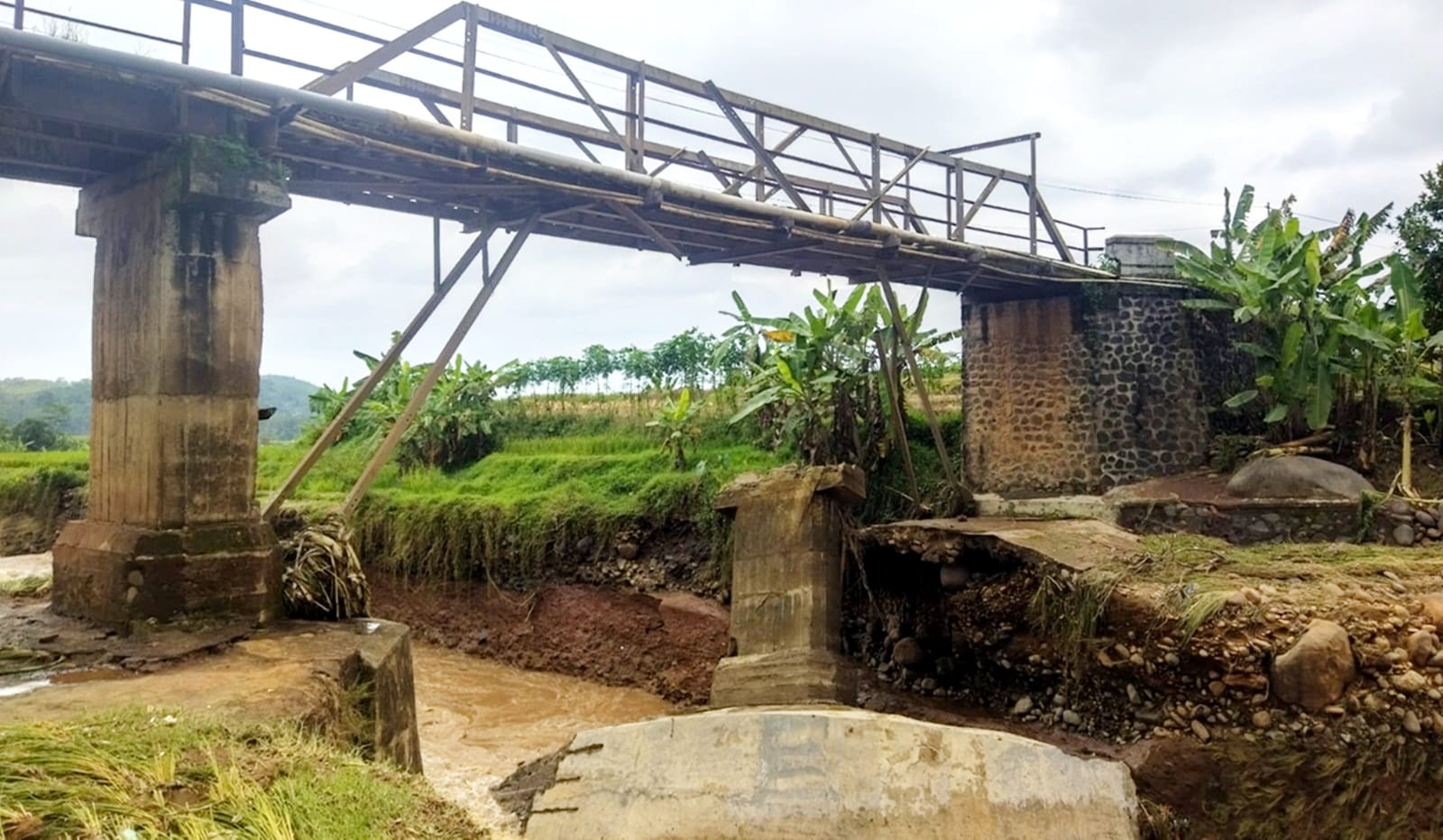 MENGGANTUNG : Pondasi jembatan Kali Petung di desa Satriyan Kecamatan Tersono terlihat sudah menggantung akibat tergerus banjir dan membahayakan.