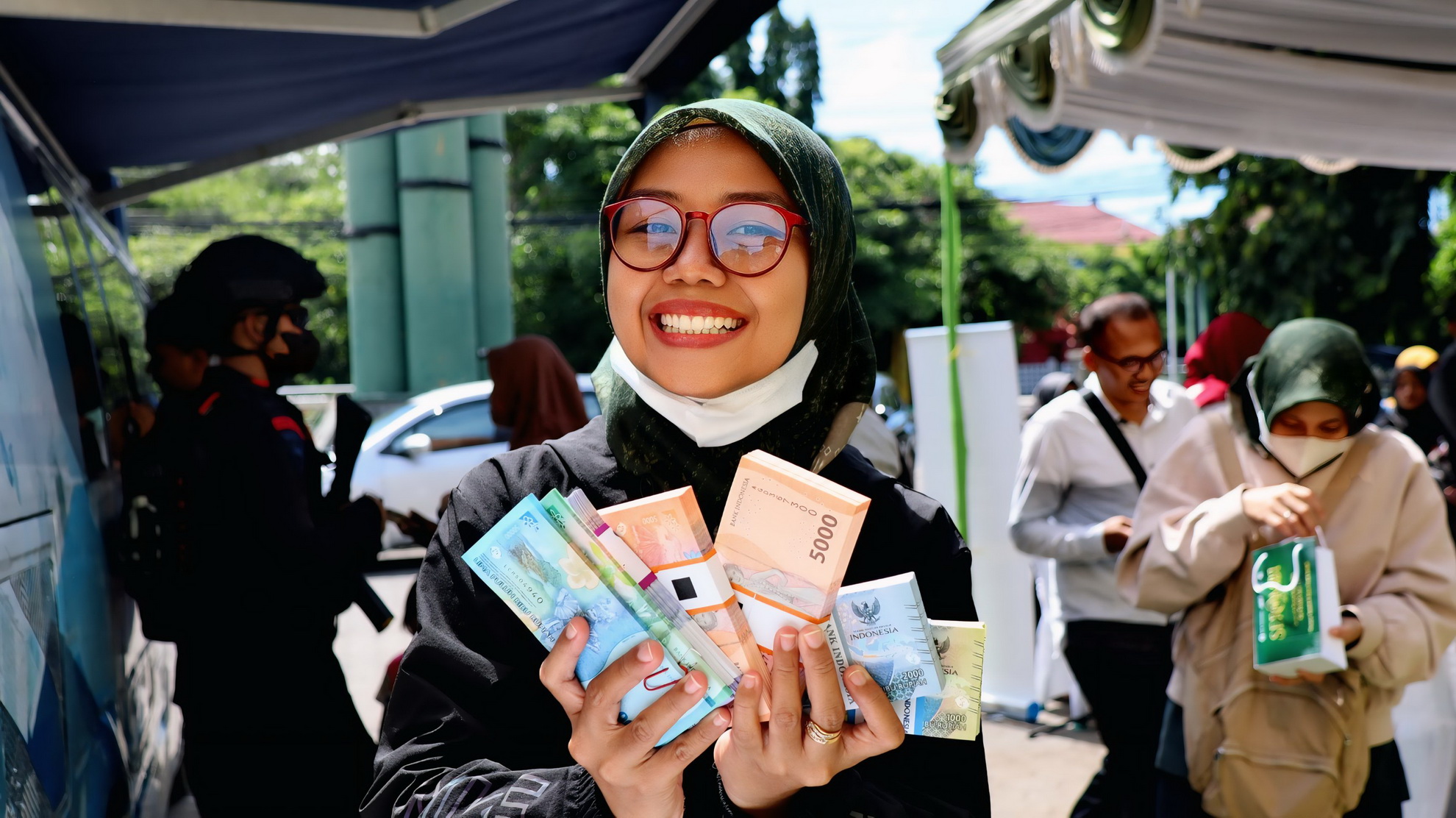 TUNJUKKAN UANG &ndash; Salah satu warga, menunjukkan uang pecahan baru usai menukar di kas keeling Bank BI di halaman Masjid Asy-Syuhada Kota Pekalongan, Selasa siang (11/3/2025).