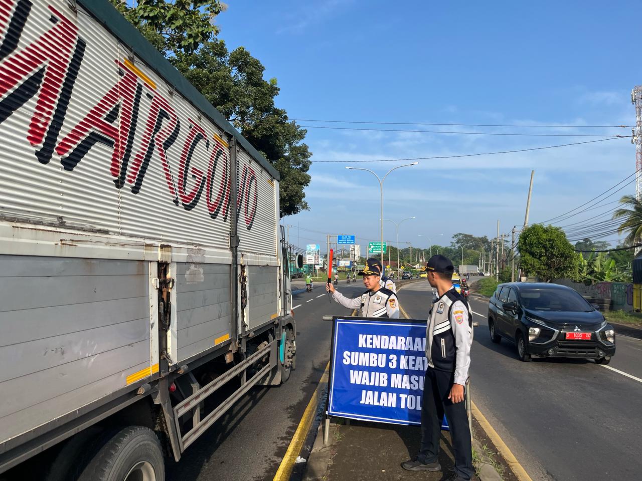 PEMBATASAN: Petugas Dishub mengarahkan truk sumbu tiga masuk jalan tol.