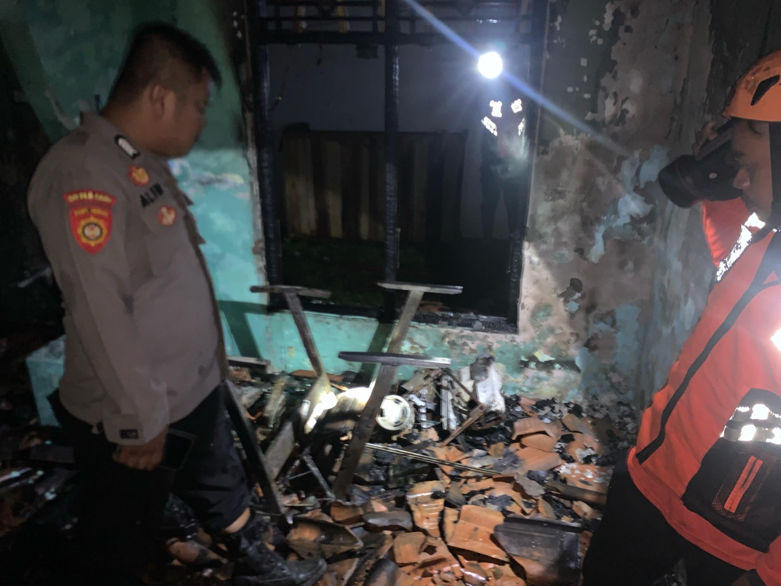 TERBAKAR: Anggota kepolisian saat masuk ke dalam lokasi kebakaran usai api berhasil dipadamkan, Sabtu (03/5/2024) malam.
