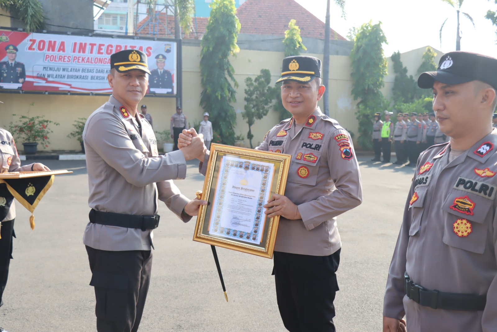 SERAHKAN -&nbsp;Kapolres Pekalongan Kota AKBP Riki Yariandi saat berikan penghargaan kepada Kompol&nbsp;Pekalongan Kota Kompol Pujiono, di halaman Mapolres setempat&nbsp;&nbsp;Senin (19/5/2025).