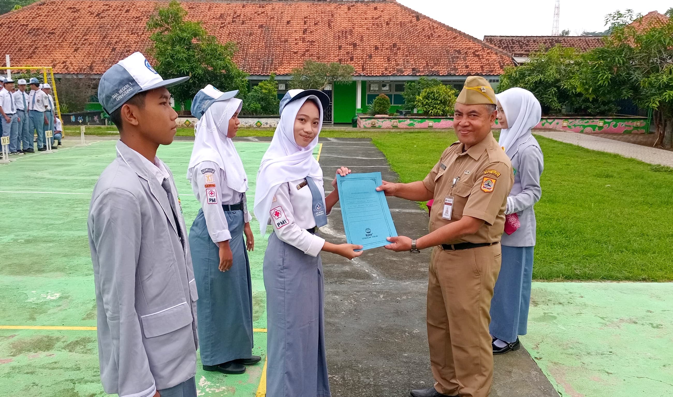 APRESIASI : Khoirun Nisa menerima penghargaan dari Kepala Sekolah SMA Negeri 1 Gringsing Wachid Mucharom, di halaman sekolah setempat, Selasa (3/6/2025).