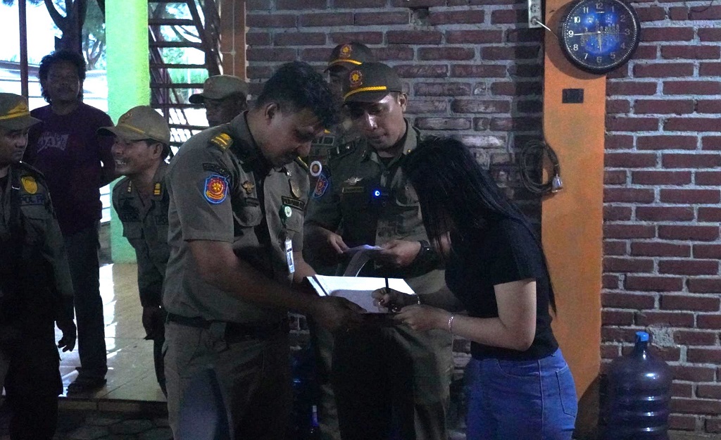 PERINGATAN: Petugas saat mengirimkan surat peringatan pada tempat-tempat hiburan di sepanjang Pantai Sigandu.
